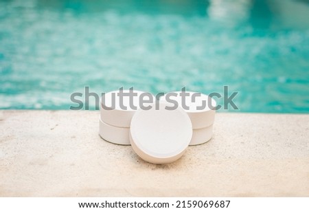 Close-up of some chlorine tablets for cleaning on the edge of a swimming pool, chlorine tablets to clean swimming pools, concept of chlorine tablets to disinfect swimming pools