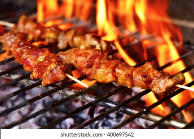 closeup of some meat skewers being grilled in a barbecue - Shutterstock ID 400697542