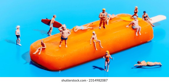 closeup of some miniature people wearing swimsuit on an orange popsicle, on a blue background, in a panoramic format to use as web banner or header - Powered by Shutterstock