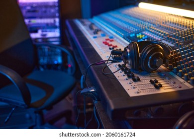 Close-up of sound mixing board with headphones on it for musical producer in studio