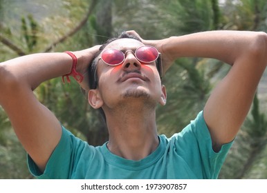 Closeup of a south asian young guy wearing sunglass and touching hair with head tilted back, People in nature