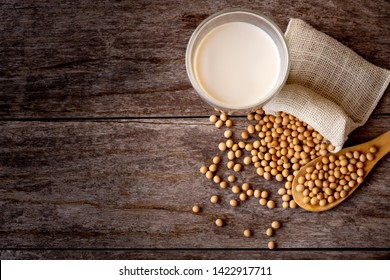 Closeup soybeans in wooden spoon and glass of soy milk isolated on old wooden table background. Vintage style. Top view.
