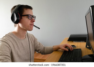 A Closeup Of A Spanish Caucasian Male Wearing A Headset And Using His Computer Indoors