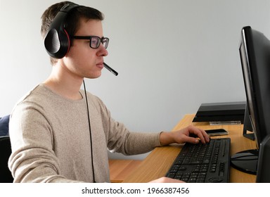 A Closeup Of A Spanish Caucasian Male Wearing A Headset And Using His Computer Indoors