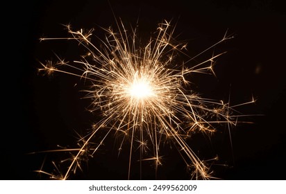 A close-up of a sparkler emitting bright sparks against a dark background. - Powered by Shutterstock