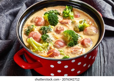 Close-up Of Spicy Broccoli Cheddar Cheese Sausage Soup In A Pot On A Black Wooden Table, Horizontal View From Above