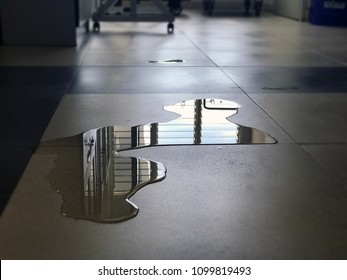 Close-up Of Spilled Water Leak On The Floor Of Building. Wet Floor From Rainy Splash Or Pipelines Water Leakage In Office. Danger Accident At Home From Liquid Slippery Floor Hazard Concept.