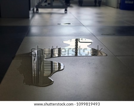 Close-up of spilled water leak on the floor of building. Wet floor from rainy splash or pipelines water leakage in office. Danger accident at home from liquid slippery floor hazard concept.