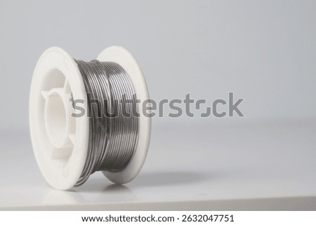 Close-up of a spool of solder wire on a white background. Ideal for electronics repair, DIY, and crafting projects.