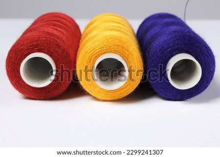 Close-up of spools with red, yellow, blue threads.