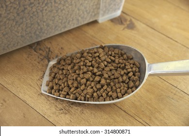 Closeup Of Spoonful Of Premium Grade Dog Food On Top Of Wooden Board With White Container Of Food In Background