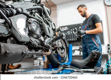 Close-up of a sports motorcycle during the maintenance or repairment with worker on the background at the workshop - Powered by Shutterstock