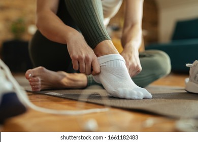 Close-up of sportswoman wearing white socks while preparing for workout at home. 