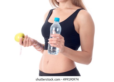 Close-up Of Sporty Girl Who Is Turned Sideways And Shows An Apple In One Hand And The Other Holding A Bottle Of Water