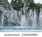 Close-up of spouts with jets of water gushing from fountain tubes, structure and green foliage of trees in background, Plaza Tapatia in historic center of city of Guadalajara, Jalisco Mexico