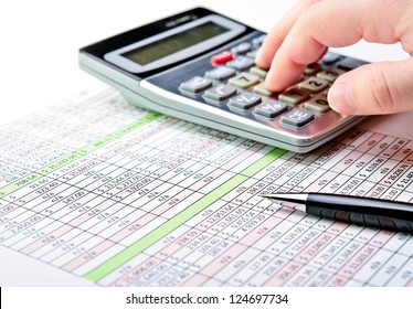 Close-up Of A Spreadsheet With Pen And Calculator.