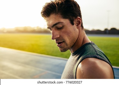 Closeup Of A Sprinter Standing On A Running Track. Runner Looking Down Standing On The Track With Sweat Dripping From Face.