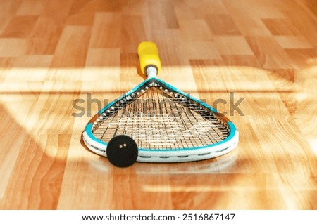 Closeup of squash racket and ball on court floor