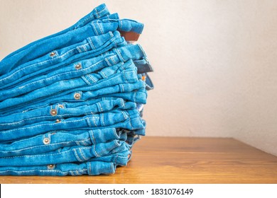 closeup of stack of blue jeans. in store on wooden shelf