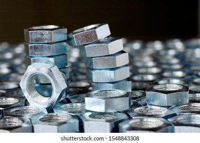 Close-up of a stack of chrome metal nuts stand on the lying nuts in the form of honeycombs next to each other. The concept of repairing fasteners and small production parts