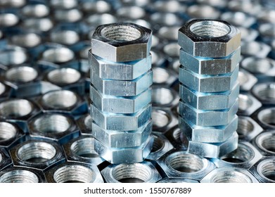 Close-up of a stack of chrome metal nuts stand on the lying nuts in the form of honeycombs next to each other. The concept of repairing fasteners and small production parts