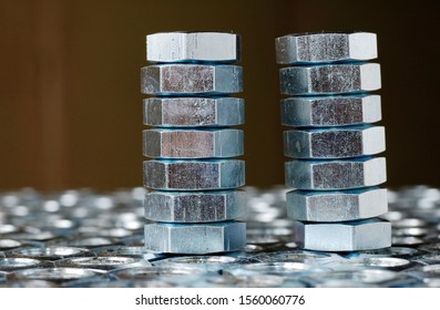 Close-up of a stack of chrome metal nuts stand on the lying nuts in the form of honeycombs next to each other. The concept of repairing fasteners and small production parts
