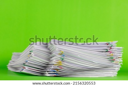 Close-up of Stack of Group report papers Document clipped in color clips on green background, business, and education concept.
