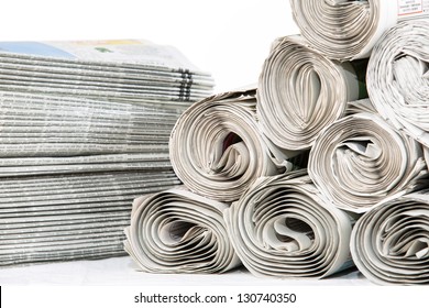 A closeup of a stack of newspapers and rolled newspapers ready to be delivered
