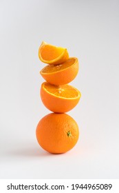 Close-up of a stack of oranges, whole and sliced, a tower of oranges on white background with copy space, vertical