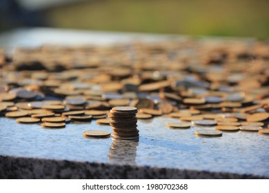 Close-up of the stack of rusty copper coins of 10 kopecks, the stack is surrounded by a bunch of coins of 10 and 50 kopecks, the coins are illuminated by golden sunlight and lie on a granite stone