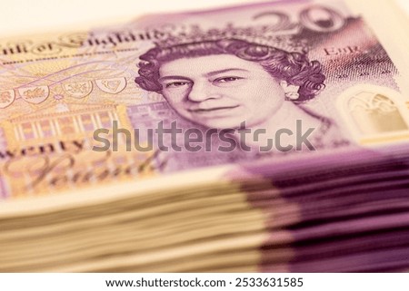A closeup of a stack of twenty pound banknotes from the United Kingdom, featuring Queen Elizabeth IIs portrait.