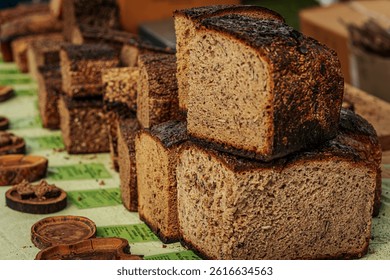 Close-up of stacked slices of dark rye bread with a rich, rustic crust and soft, airy texture. Some pieces include seeds, showcasing artisanal baking quality.