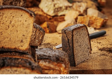 Close-up of stacked slices of dark rye bread with a rich, rustic crust and soft, airy texture. Some pieces include seeds, showcasing artisanal baking quality.