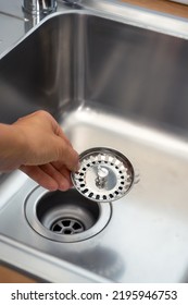 Close-up Of A Stainless Steel Sink Plug Hole In The Hands Of The Kitchen Hostess.