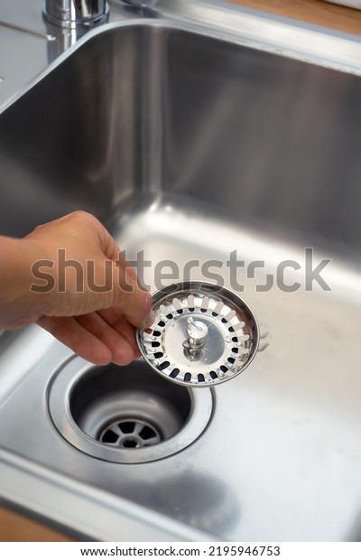 close-up of a stainless steel sink plug hole in\
the hands of the kitchen\
hostess.