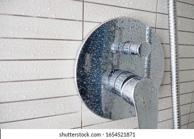 Closeup of stainless steel water faucet with water drops installed on the concrete wall in the bathroom for shower and bathing. Modern style of bathroom interior
