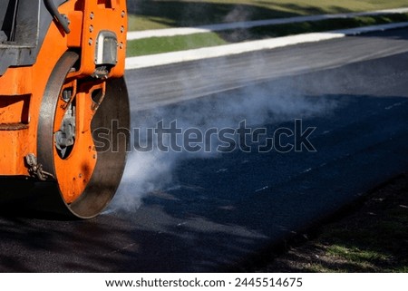 Closeup of steamroller compacting freshly load asphalt, residential road repaving construction project
