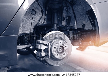 Closeup steel brake disk and detail of wheel hub in garage car service, with sunlight.