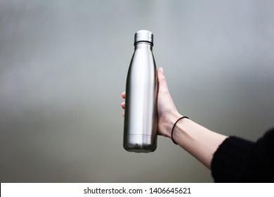 Close-up of steel eco thermo water bottle in female hand.