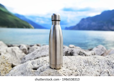 Close-up of steel eco thermo water bottle on the background of the lake in the mountains. Be plastic free. Zero waste. Copy space. Zero waste, no plastic.