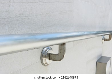 Close-up steel railing structure installed on granite tile wall.