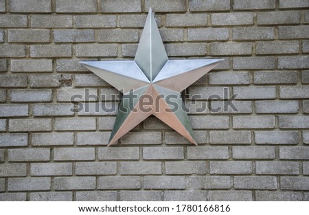 close-up of a steel  silver star on a gray brick wall.copy space