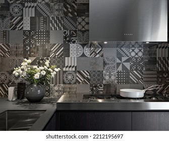 Close-up Of Steel Worktop In Modern Kitchen With Stove And White Flowers Pot