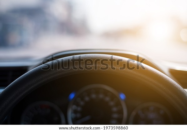 Close-up of the steering wheel\
in the car with the background of sunset. View of the road, View\
through the car windscreen. Driving during sunset on the city\
road.