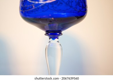 Closeup Of The Stem Of A Vintage Bohemian Crystal Wine Glass In Color Cobalt Blue  On A Soft Warm Colored Background. Old Glassware.