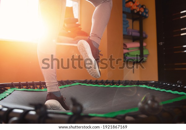 Closeup step fitness woman jumping on mobile\
mini trampoline.