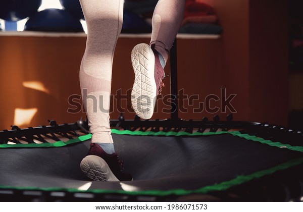Closeup step fitness woman jumping on mobile\
mini trampoline.