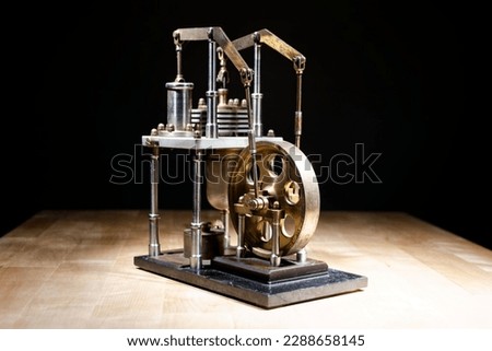 closeup of a stirling engine construction with wooden table and black background