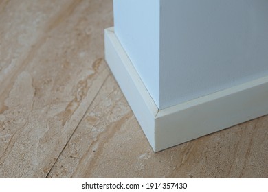 Close-up Of Stone Marble White Plinth Covers The Joints Between Wall With Laminate Or Stone Flooring.