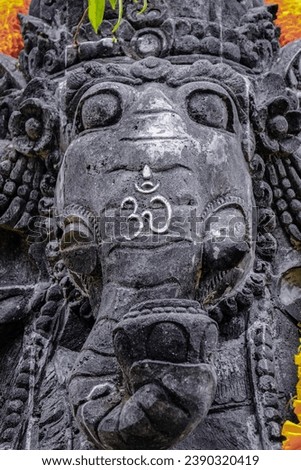 Close-up of a stone sculpture of Lord Ganesha with an ohm symbol on it's trunk.